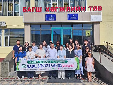 글로벌 서비스러닝 팀원들과 교수님들이 현수막을 들고 웃고 있다.